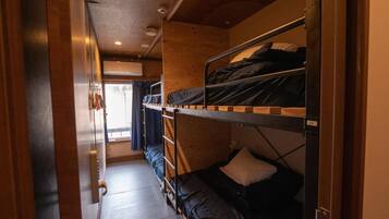 A narrow corridor with bunk beds on one side and a window at the end.