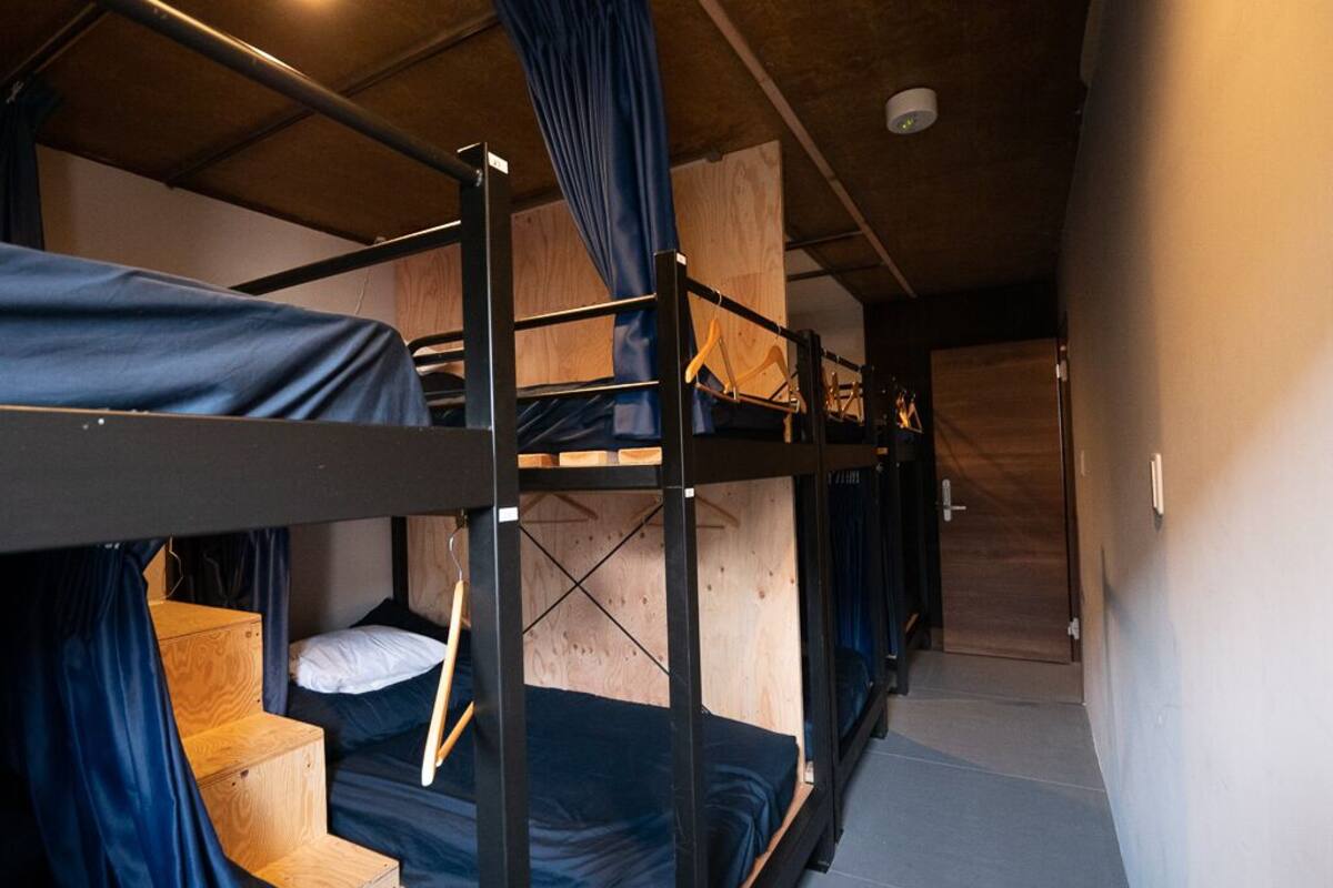 A bunk bed room with wooden bunk beds, blue curtains, and a wooden door.