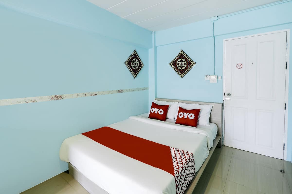 Une chambre avec un lit, deux oreillers ornés du logo « OYO », une porte blanche et deux éléments de décoration murale.