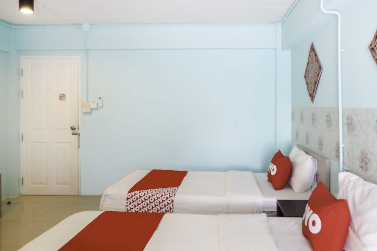 Une chambre avec deux lits, une porte blanche et un mur bleu clair.
