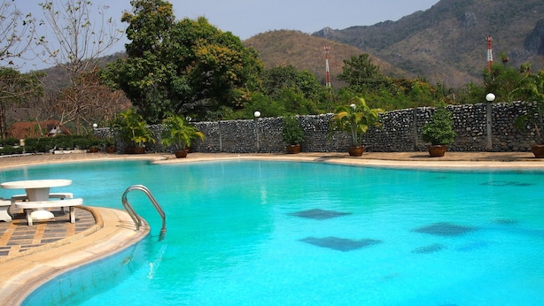 Ein klarer Swimmingpool mit einer Steinmauer und Blumentöpfen.