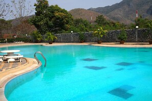 Une piscine aux eaux cristallines, bordée d’un mur en pierre et agrémentée de plantes en pot.