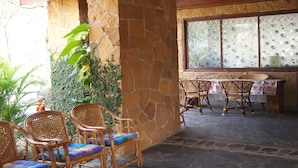 Eine Terrasse mit Steinmauern, Korbmöbeln und einem Tisch mit Blumenmuster.