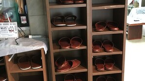 A shoe display rack with multiple shelves holding various pairs of shoes. - Aoi Business Hotel (Fukuyama)