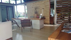 A modern interior with a wooden reception desk, a chair, and a tiled floor. - K2 Eco Boutique Lombok (Mataram)
