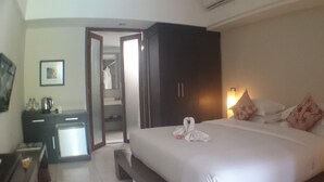 A hotel room with a bed, a desk, a wardrobe, and a bathroom visible through an open door. - K2 Eco Boutique Lombok (Mataram)