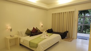 Une chambre d’hôtel avec un lit, des tables de chevet, un bureau, une chaise et une vue sur la verdure par la fenêtre.