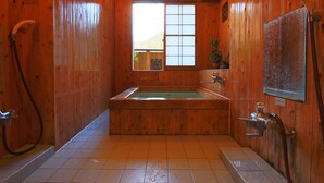 Une salle de bain rustique, avec une baignoire, une douche et une fenêtre.