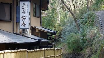 A traditional Japanese building with a bamboo fence and a signboard.