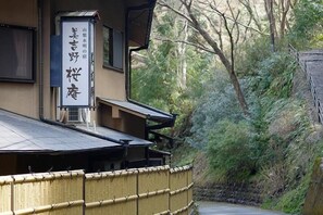 A traditional Japanese building with a bamboo fence and a signboard. - Miyoshino Sakuraan (Yoshino)