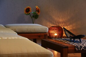 A room with a wooden table, a patterned table runner, a pair of black shoes, and a lit candle. - Miyoshino Sakuraan (Yoshino)