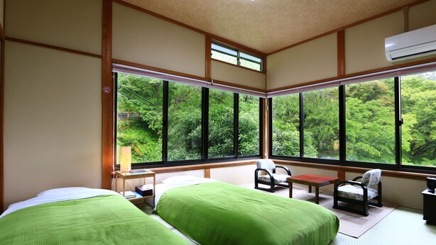 Une chambre avec deux lits, une chaise, une petite table et une fenêtre donnant sur un paysage verdoyant.