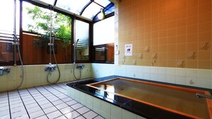 Une salle de bain équipée d’une baignoire, d’une douche et d’une fenêtre donnant sur un espace verdoyant.