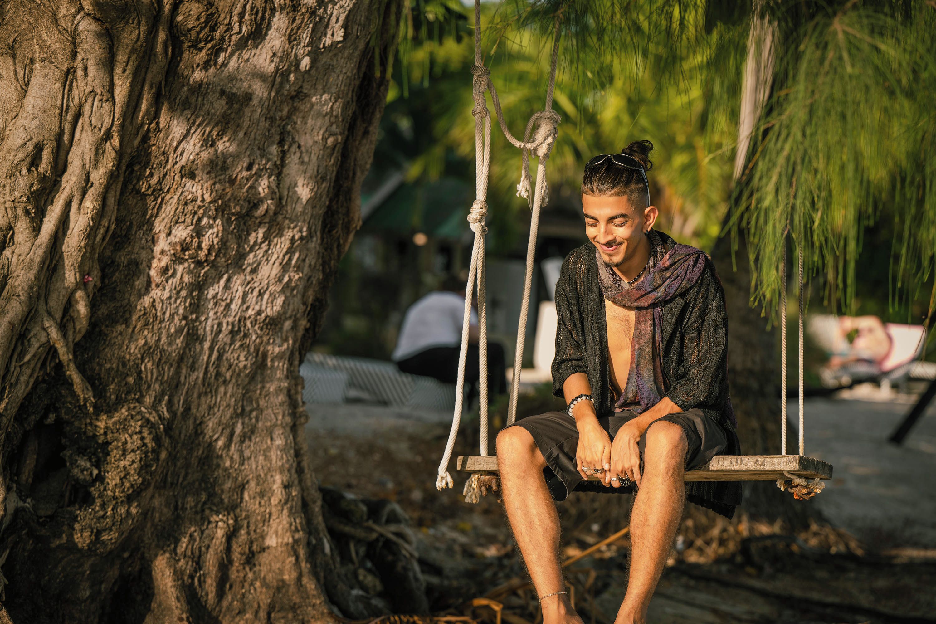 A person sitting on a swing attached to a tree.