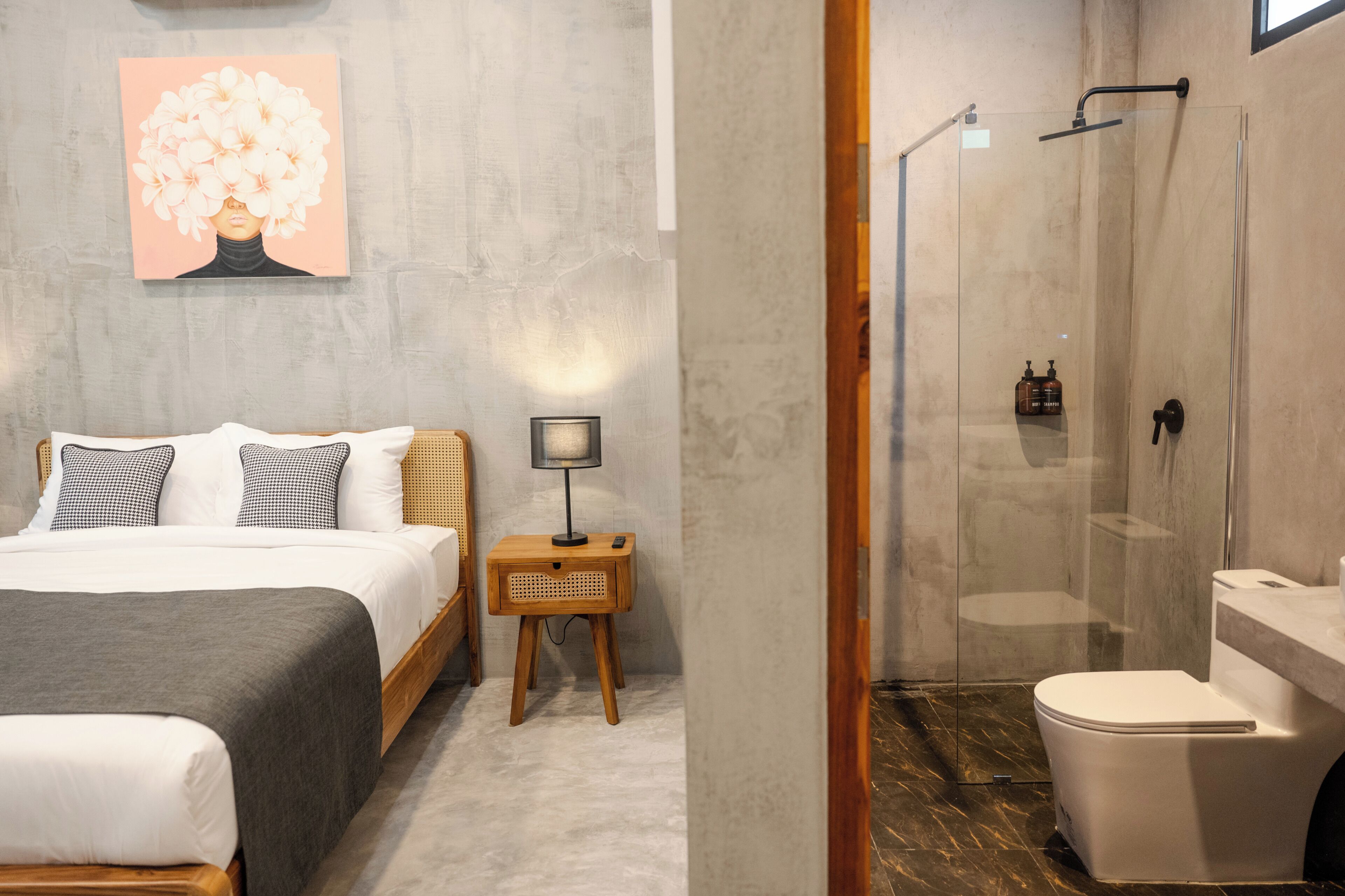 A bedroom with a bed, bedside table, lamp, and a wall-mounted artwork.