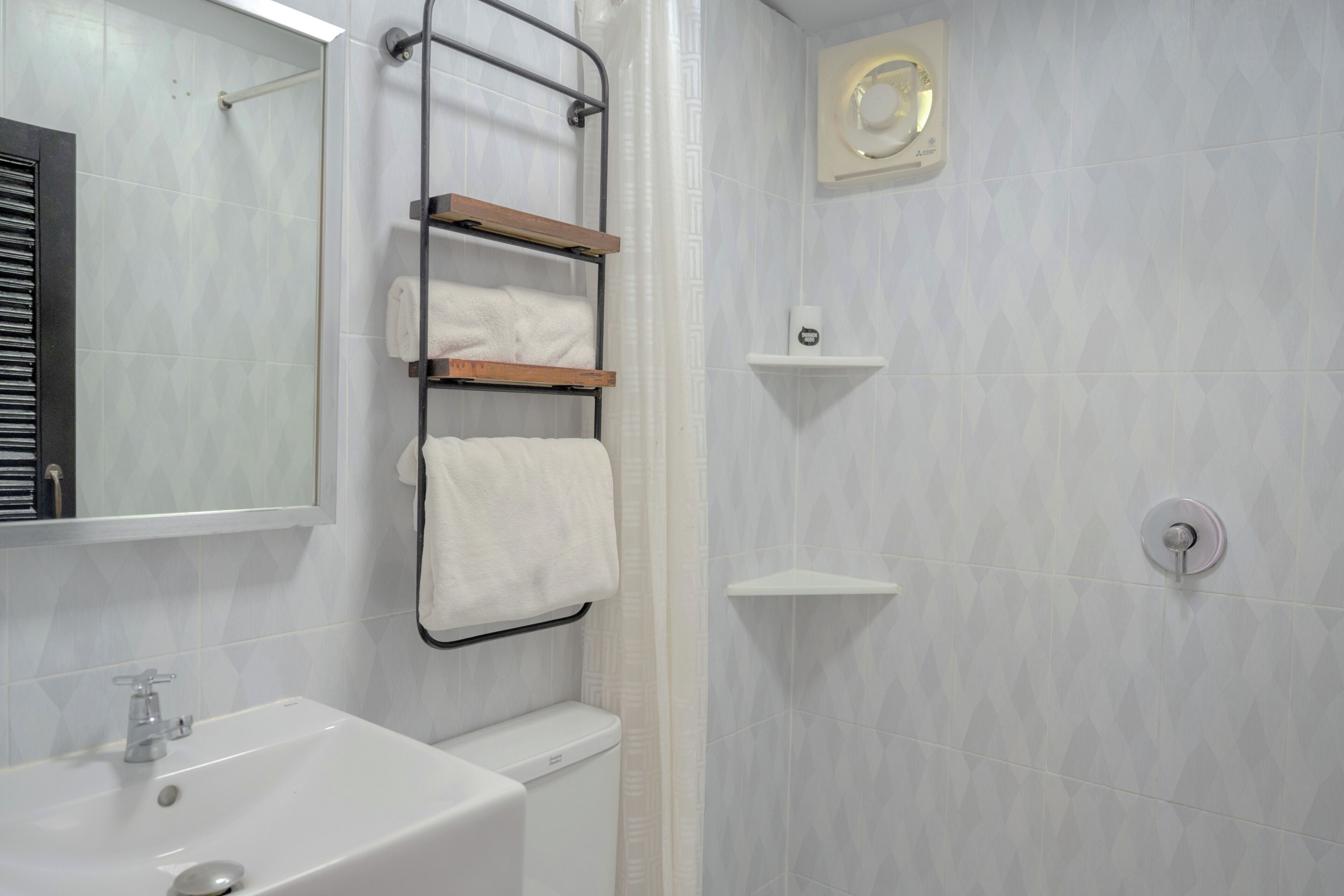 Ein Badezimmer mit einem weißen Waschbecken, einer Toilette, einem Handtuchhalter und einer Duschkabine mit Bedienfeld.