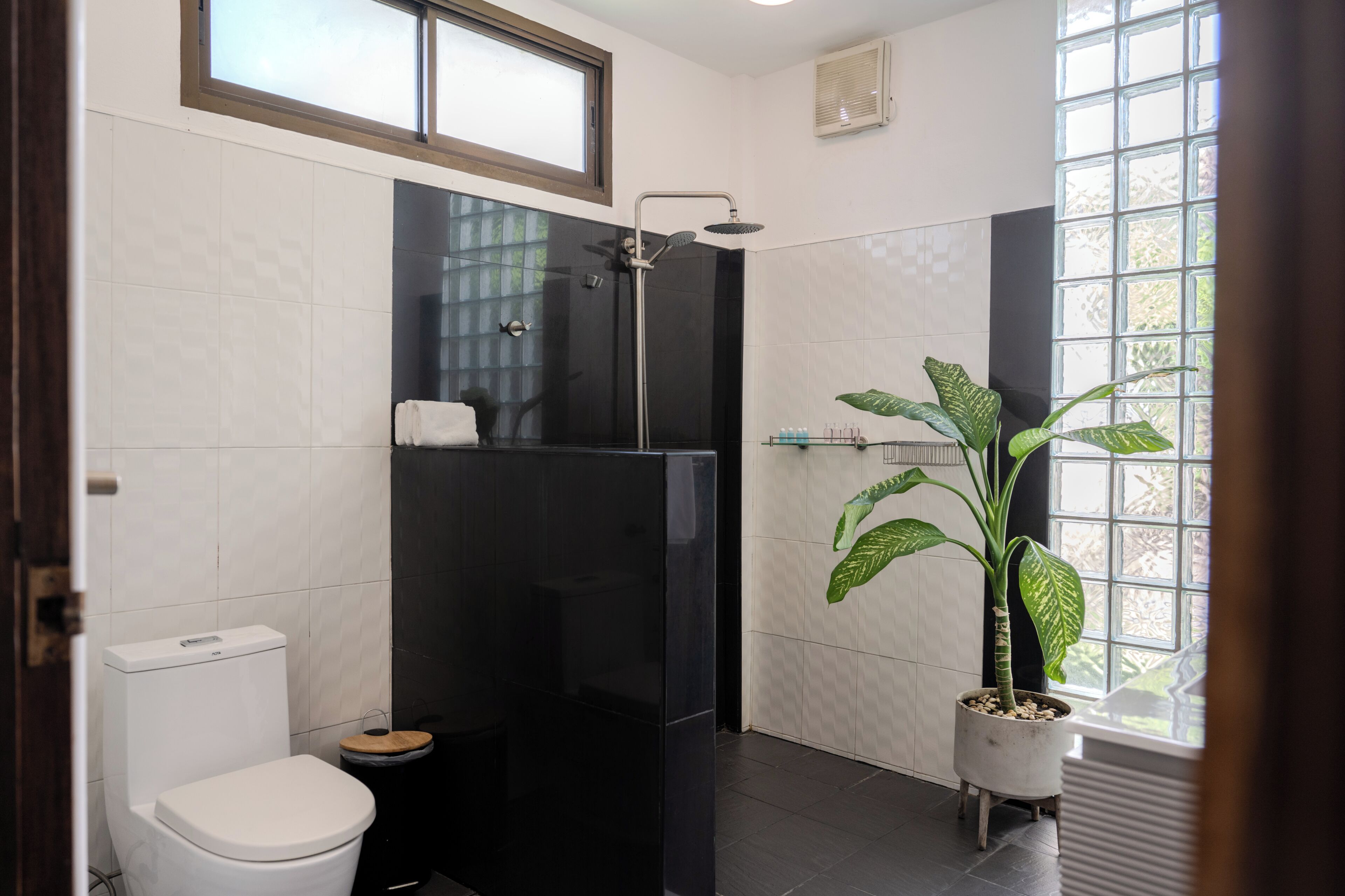 Ein modernes Badezimmer mit Toilette, Duschkabine und einer Topfpflanze.