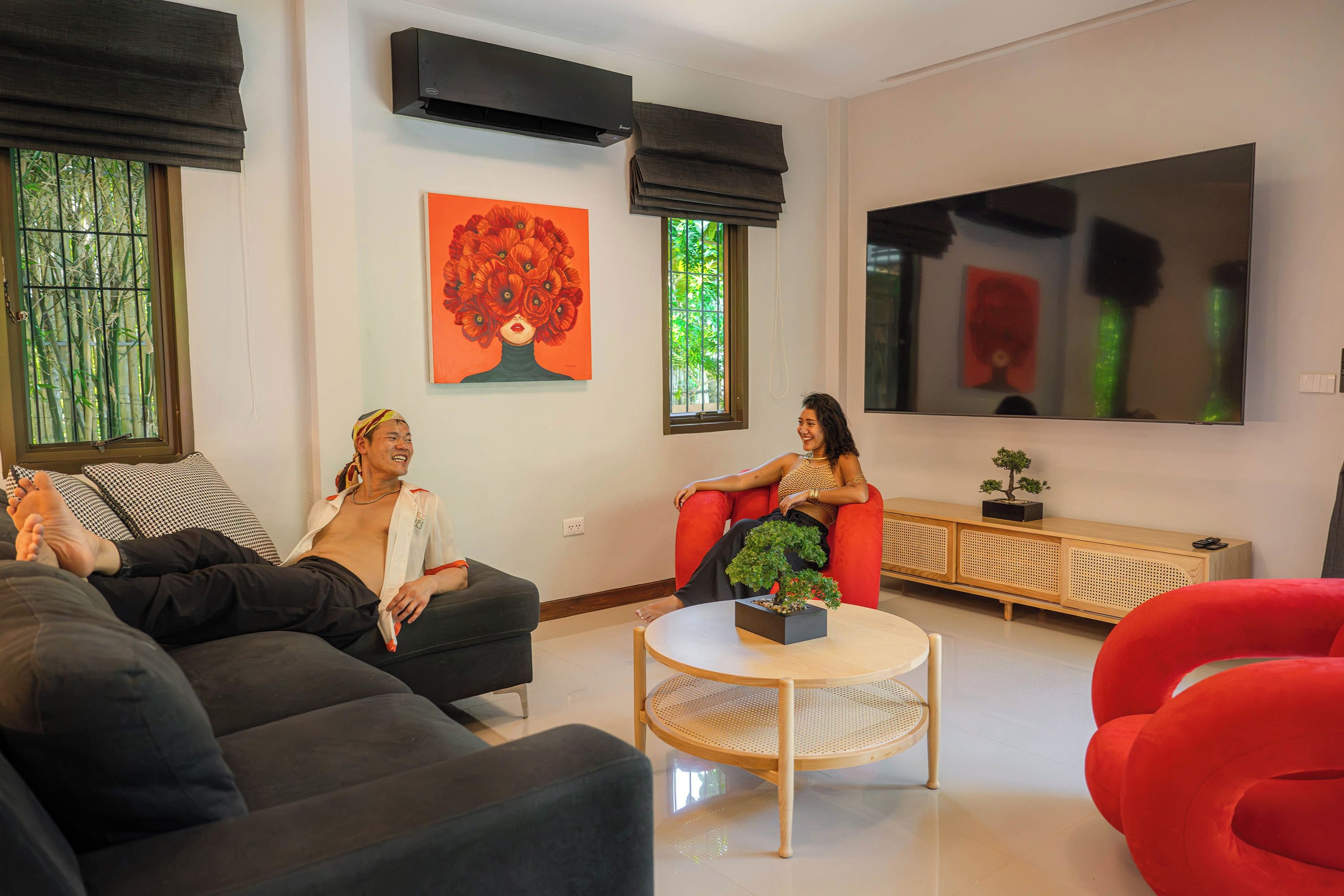 Een moderne woonkamer met een zwarte bank, een rode fauteuil en een ronde salontafel.