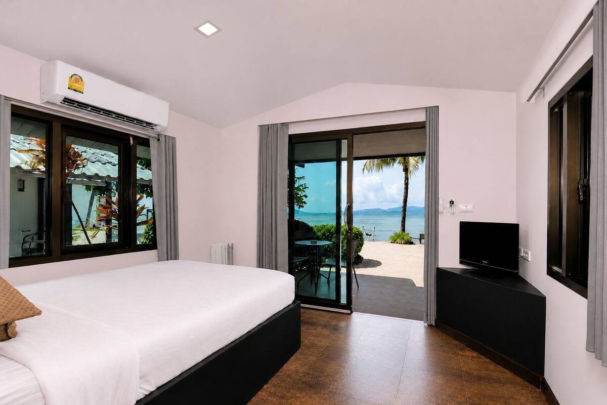 Un dormitorio con cama, televisor y vista al mar.
