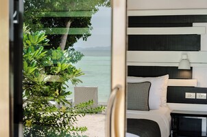 Un dormitorio con cama, mesita de noche, lámpara y vista al mar.