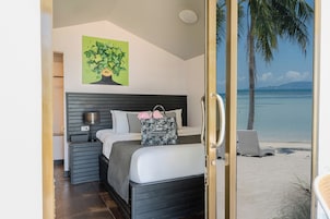 Un dormitorio con cama, mesita de noche, lámpara y un cuadro de un árbol.