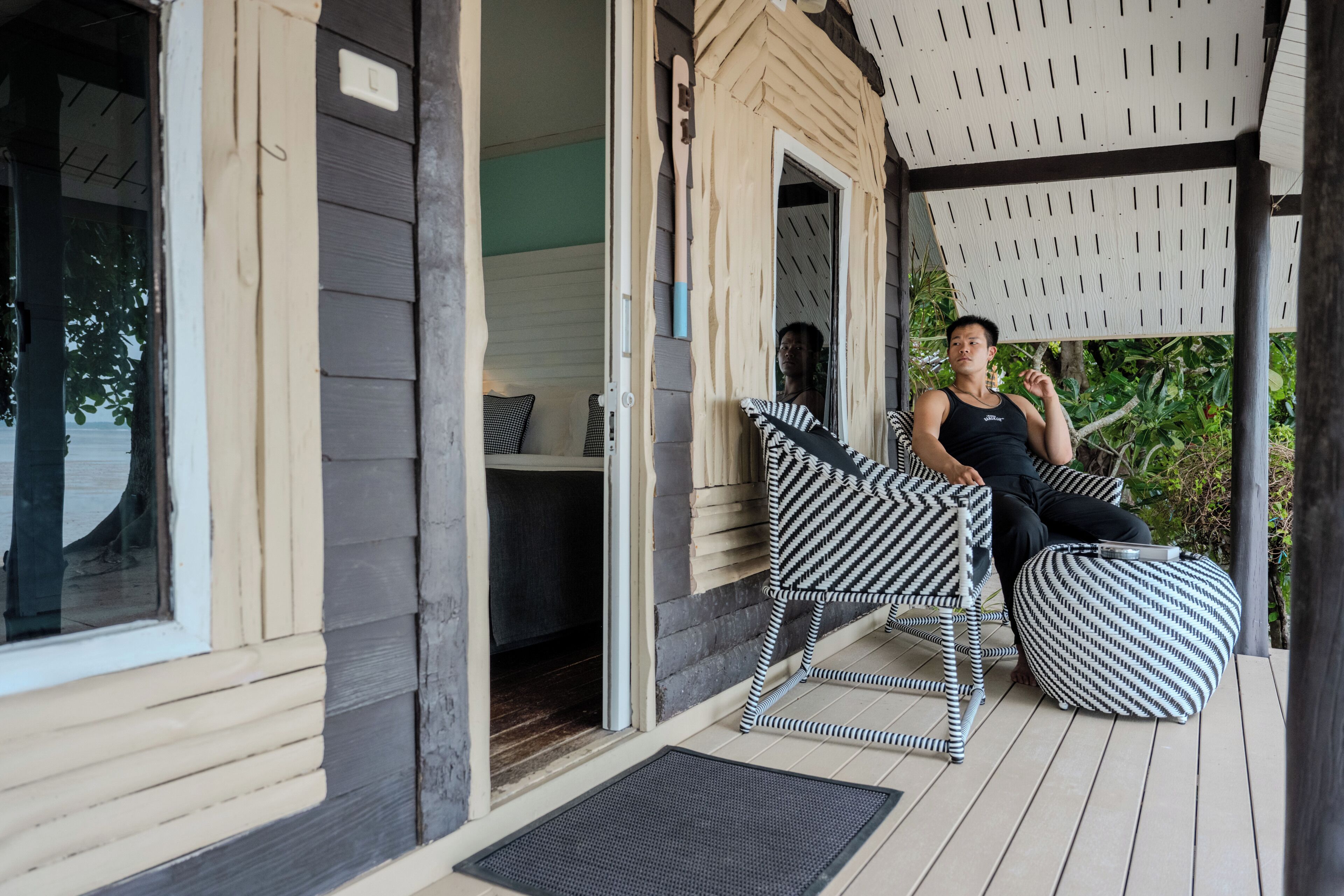 A covered outdoor seating area with a wooden deck, a bench, and a cushioned seat.