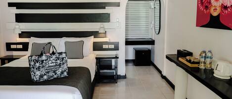 Una habitación de hotel con una cama, mesitas de noche, un escritorio, un espejo y un cuadro.