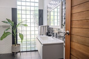Uma casa de banho moderna com uma janela ampla, um vaso de plantas e uma banheira branca.