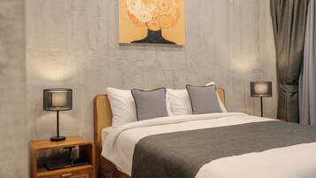 A bedroom with a bed, two bedside tables, a lamp, a painting, and a curtain.