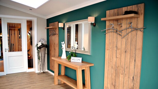 A room with a wooden bench, a mirror, and a 'WELCOME' sign. - Hotel Restaurant Burgerklause Tapken (Garrel)