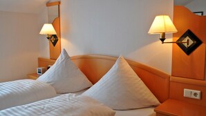 A hotel room with two beds, a nightstand, a lamp, and a mirror. - Hotel Restaurant Burgerklause Tapken (Garrel)