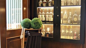 A bar area with wooden cabinets displaying bottles, a sign with family rules, and a window with blinds. - Hotel Restaurant Burgerklause Tapken (Garrel)