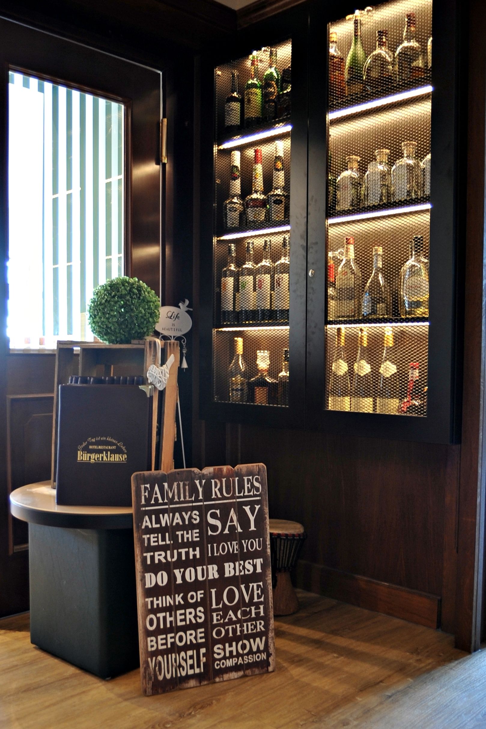 Eine Bar mit Regalen voller Flaschen und einem Schild mit Familienregeln.