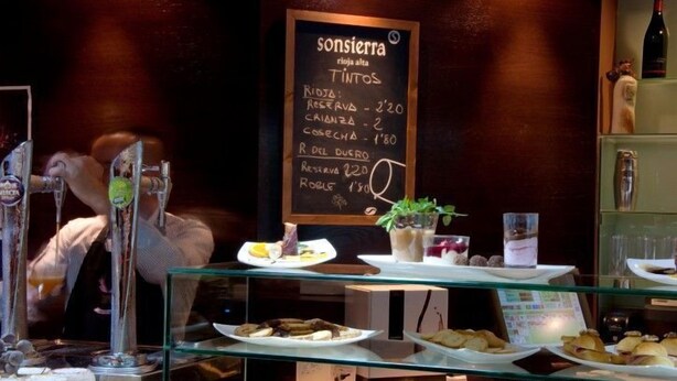 Un restaurant dont le menu est écrit à la craie sur un tableau, avec la liste des différents plats et leurs prix.