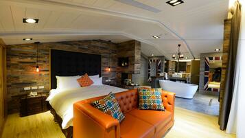 A modern bedroom with a large bed, an orange sofa, a bathtub, and a wooden accent wall.