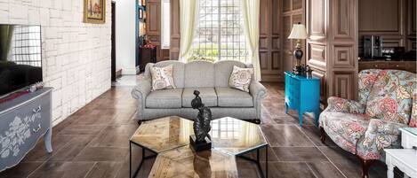 A living room with a sofa, armchairs, a coffee table, and a TV.