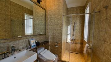 A bathroom with a large mirror, a sink, a toilet, and a glass-enclosed shower area.