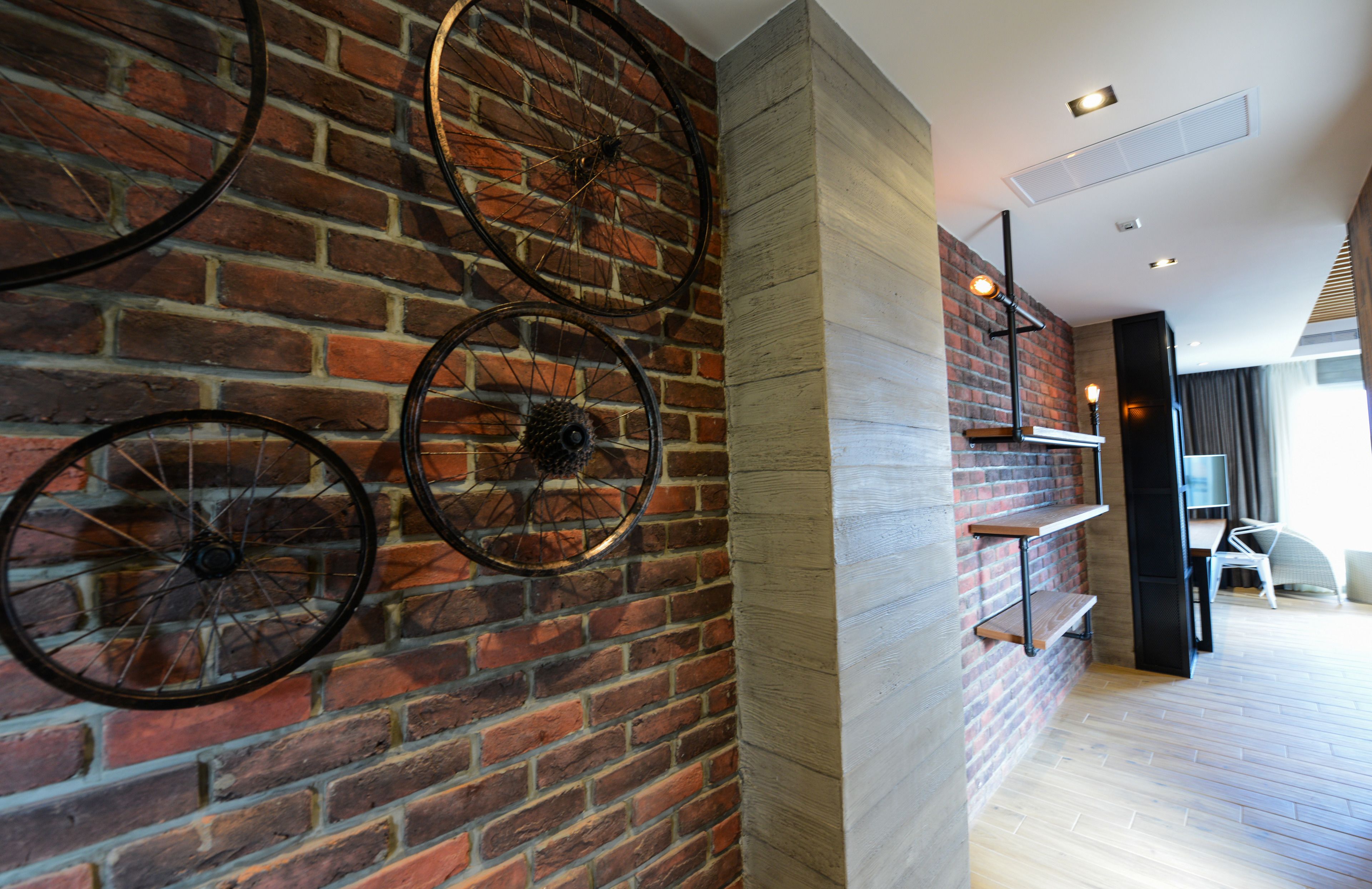 A room with a brick wall, wooden floor, and a white chair.