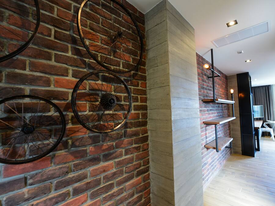 A room with a brick wall, wooden floor, and a white chair.