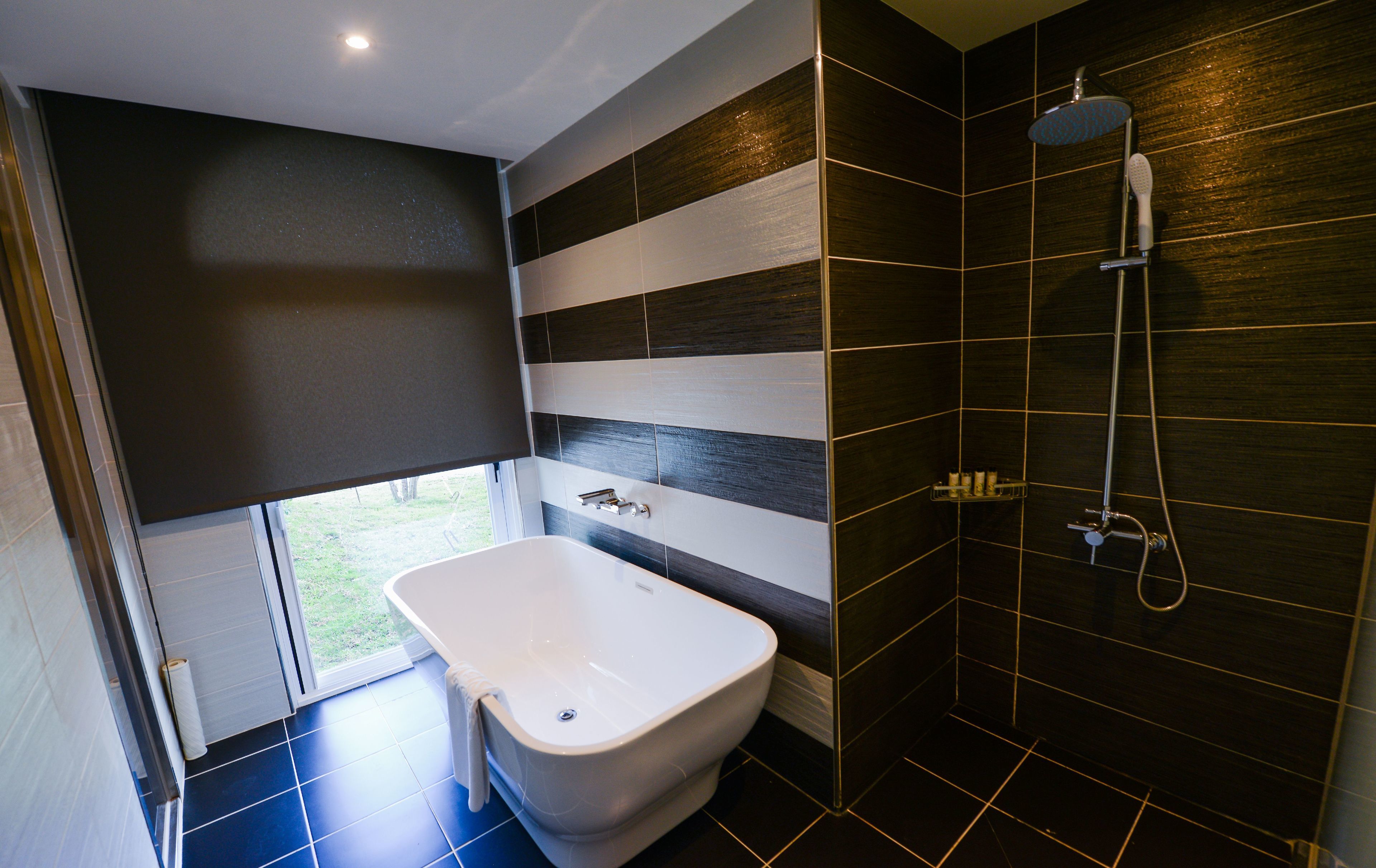 A modern bathroom with a bathtub, a shower, and a window.