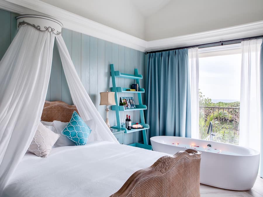 Un dormitorio con cama con dosel, una bañera y vistas al exterior.