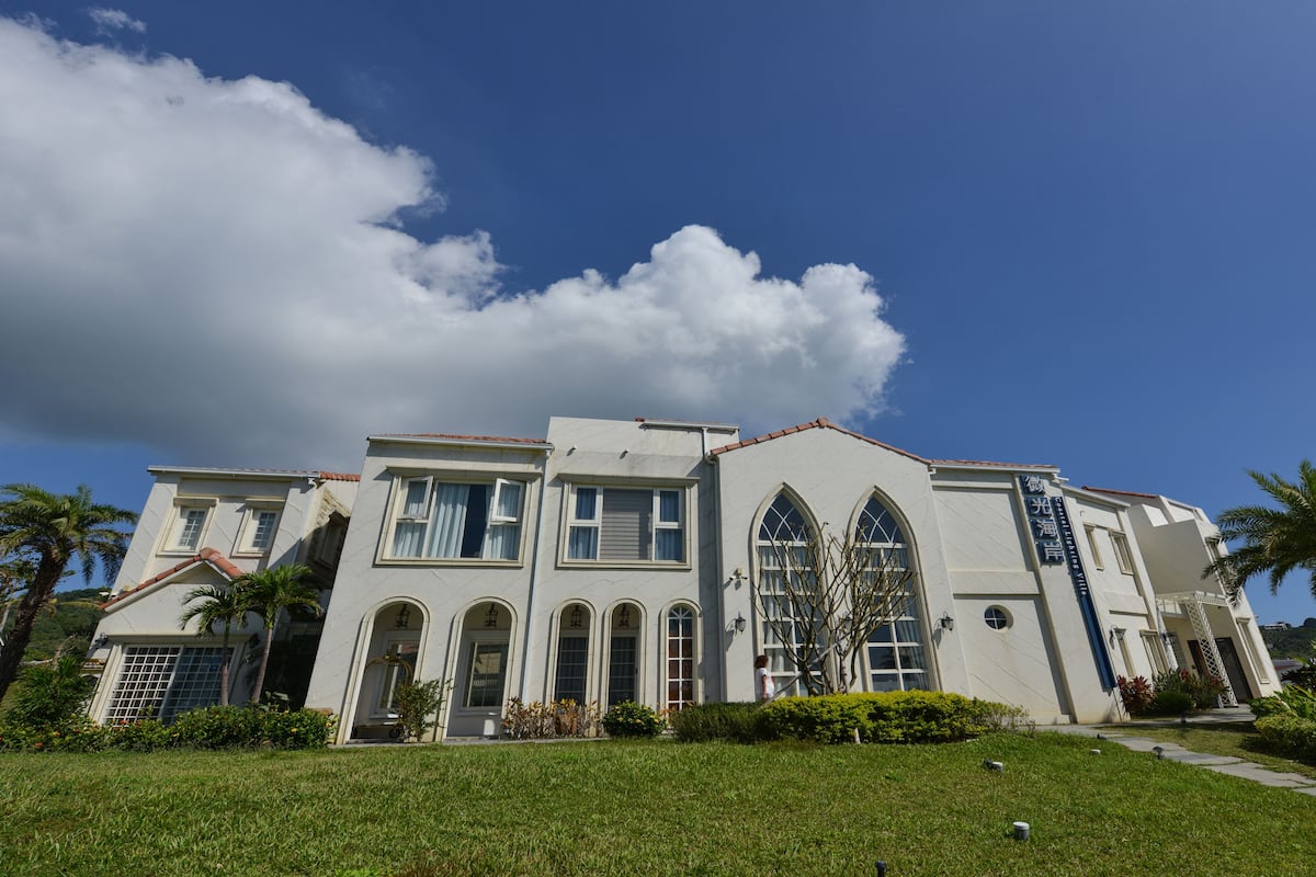 A large, white building with arched windows and a sign that reads "Hotel".
