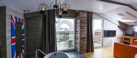 A modern bathroom with a freestanding bathtub, a large window with a view of the sea, and a wooden ceiling.