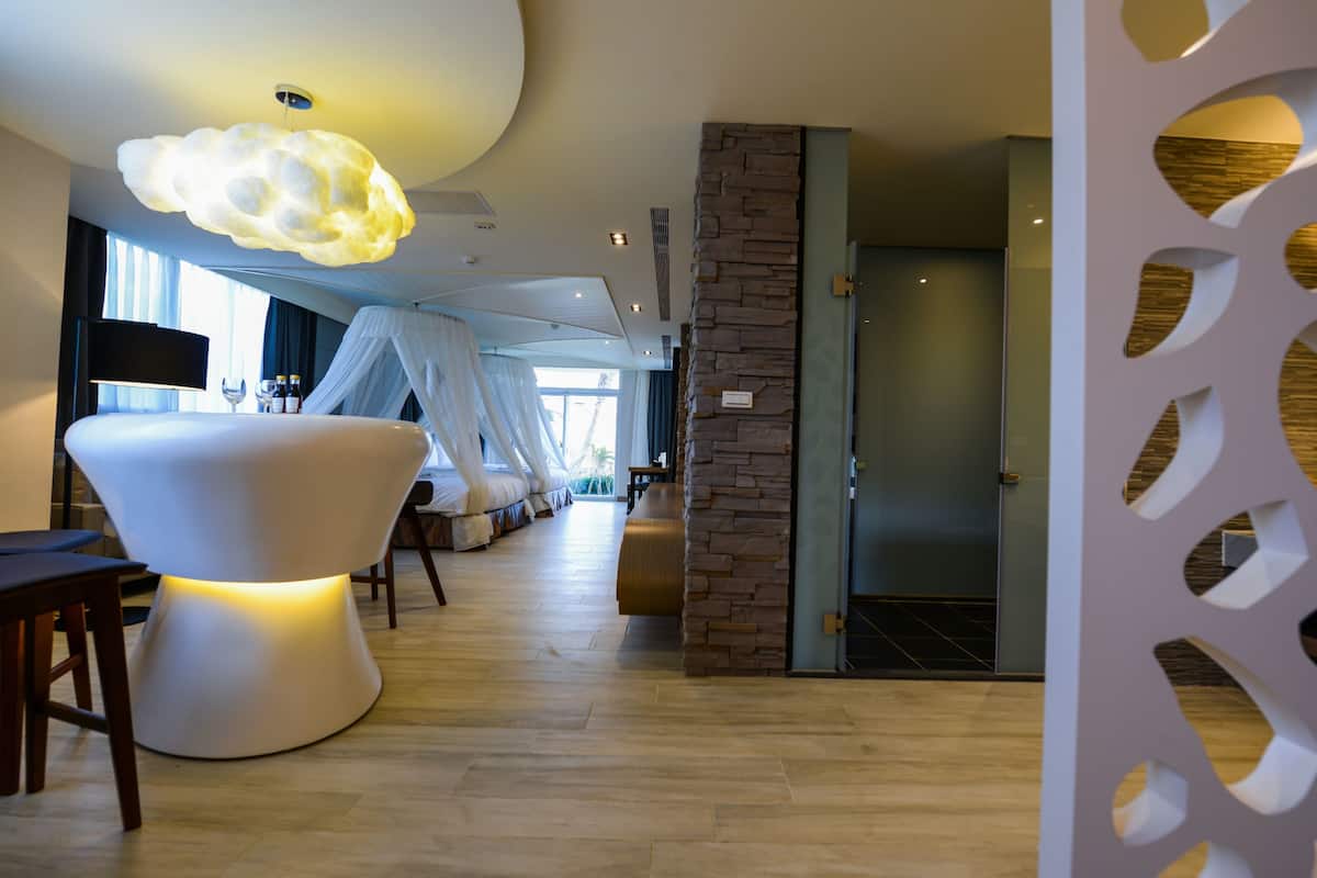 A modern hotel lobby with a large white chair, a unique ceiling light, and a stone accent wall.