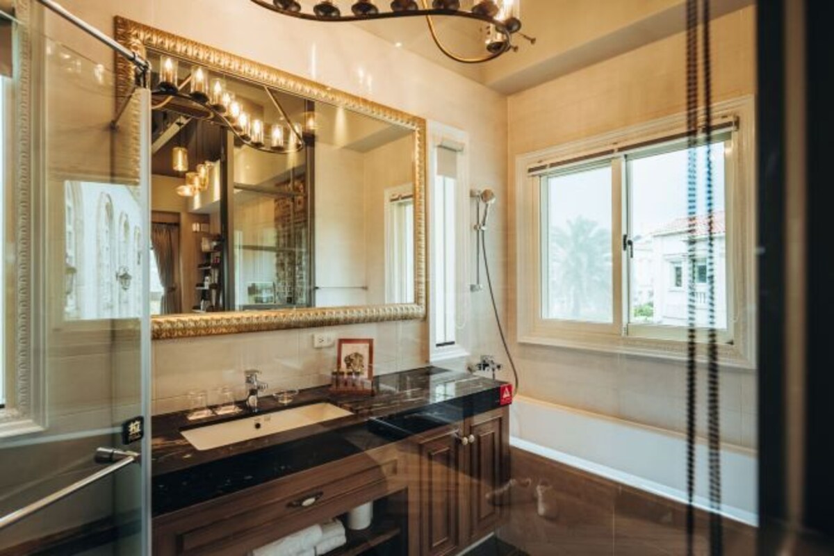 A bathroom with a large mirror, a sink, and a shower.