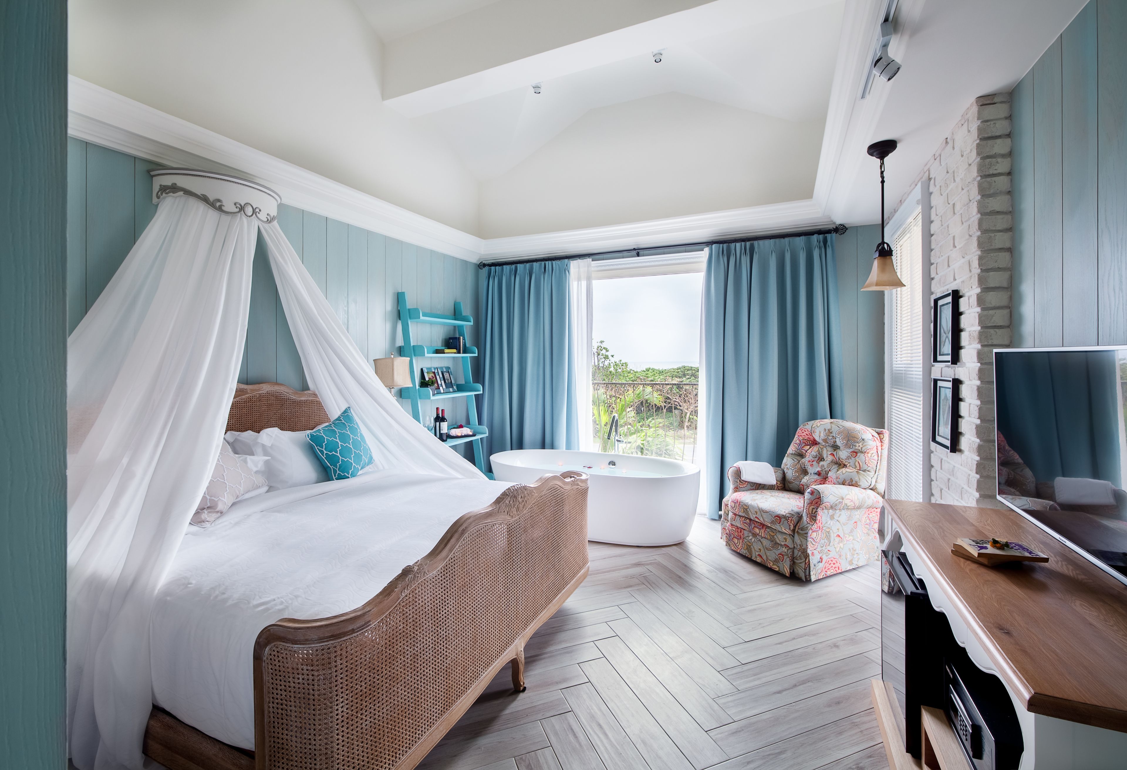 Une chambre à coucher avec un lit à baldaquin, une baignoire, un fauteuil et un téléviseur.