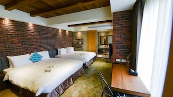 Una habitación de hotel con dos camas, una mesa de madera y una pared de ladrillo.