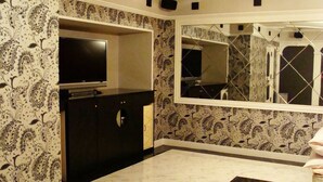 A bathroom with a large mirror, a vanity with a TV, patterned wallpaper, and a marble floor. - Hotel Alten (Osaka)