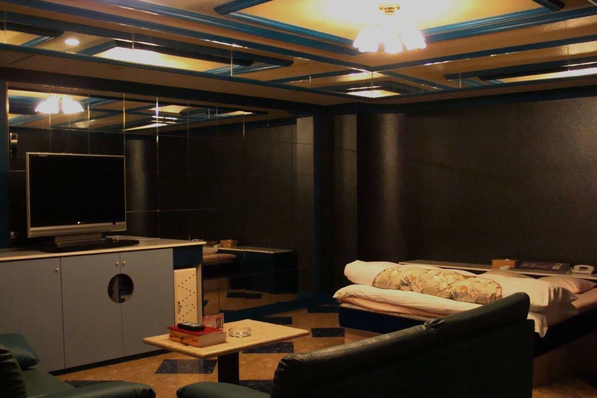 A modern hotel room with a bed, a desk, a television, and a seating area.