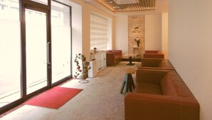 A modern lobby with a patterned ceiling, a red carpet, a fireplace, and a seating area with sofas and a coffee table. - Hotel Alten (Osaka)